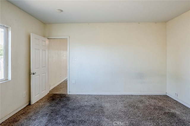 unfurnished room featuring dark carpet