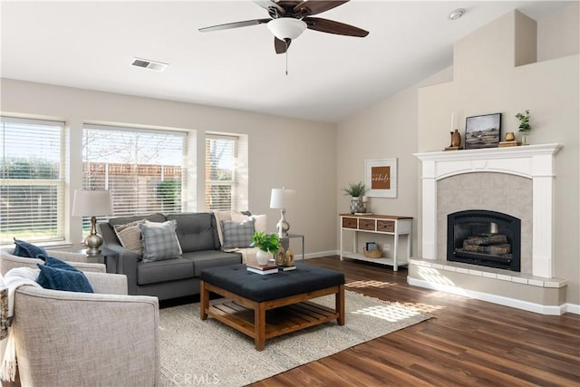 living room with hardwood / wood-style flooring, lofted ceiling, a tiled fireplace, and a wealth of natural light