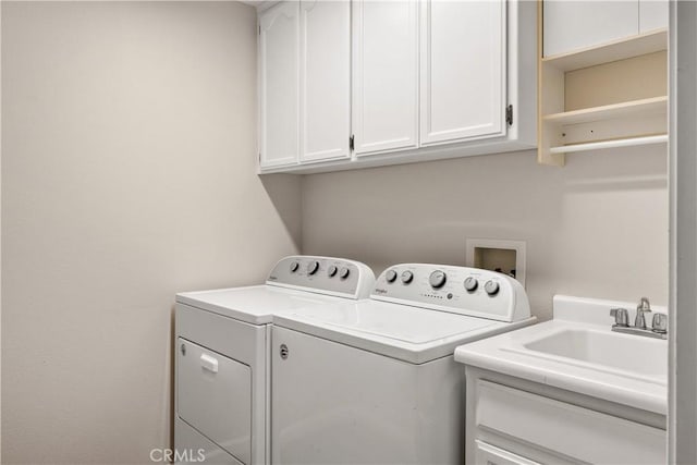 clothes washing area featuring separate washer and dryer, sink, and cabinets