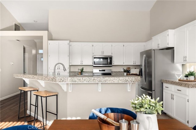 kitchen featuring stainless steel appliances, a breakfast bar, sink, and white cabinets