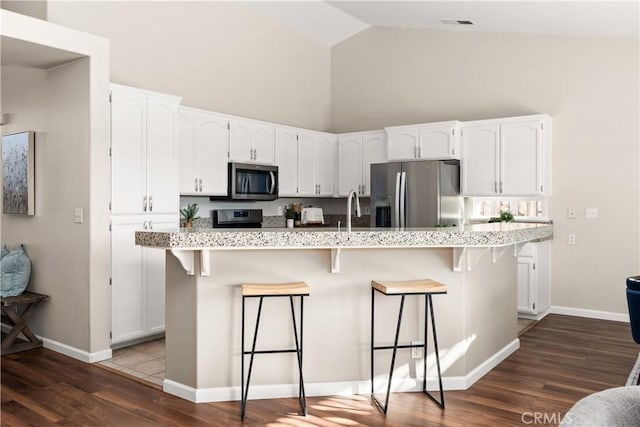 kitchen with white cabinetry, appliances with stainless steel finishes, a breakfast bar, and a kitchen island with sink