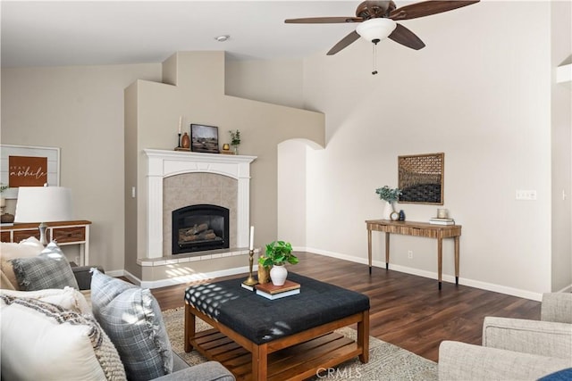 living room featuring ceiling fan, lofted ceiling, dark hardwood / wood-style floors, and a tiled fireplace