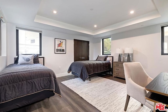 bedroom with wood-type flooring and a tray ceiling