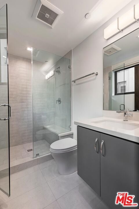 bathroom featuring vanity, tile patterned flooring, a shower with shower door, and toilet