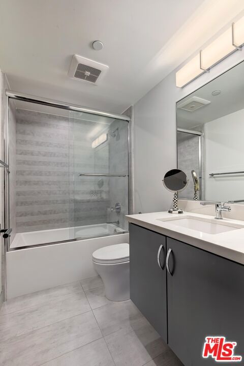 full bathroom featuring bath / shower combo with glass door, vanity, and toilet