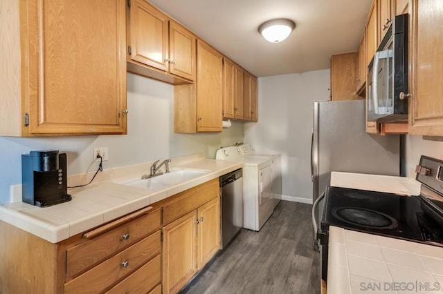 kitchen featuring sink, dark hardwood / wood-style flooring, separate washer and dryer, stainless steel appliances, and tile countertops