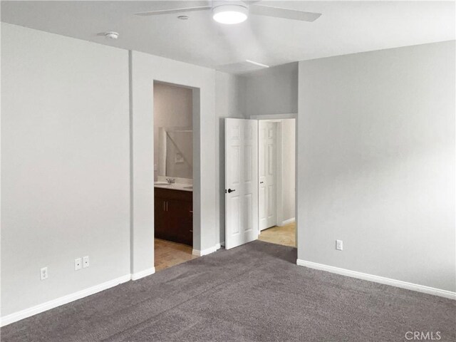 unfurnished bedroom featuring ceiling fan, ensuite bath, sink, and light carpet