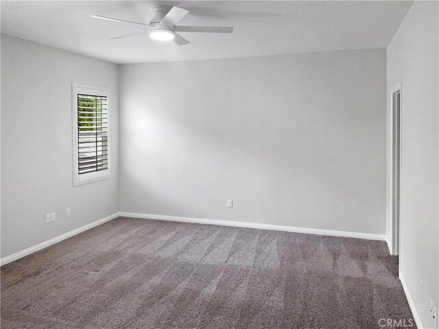 empty room with ceiling fan and dark colored carpet