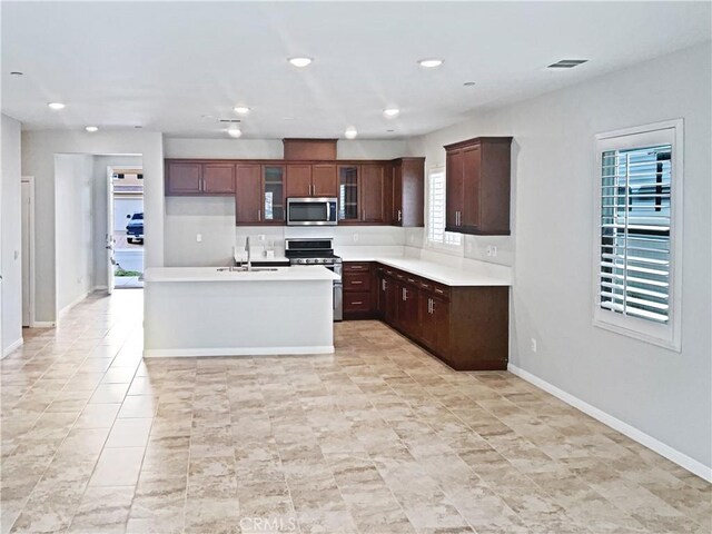 kitchen with stainless steel appliances, sink, and a center island with sink