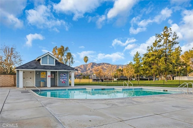 view of pool with a mountain view, a patio area, a lawn, and an outdoor structure