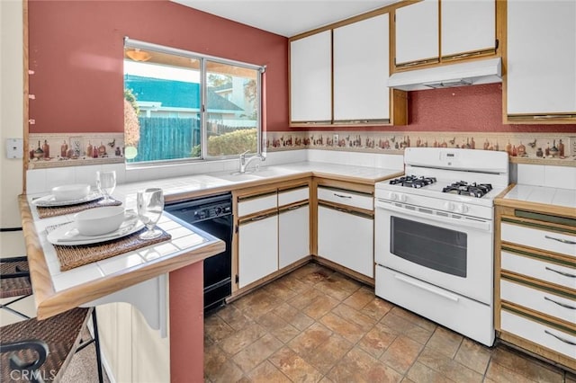 kitchen featuring dishwasher, white cabinets, sink, white range with gas stovetop, and tile countertops