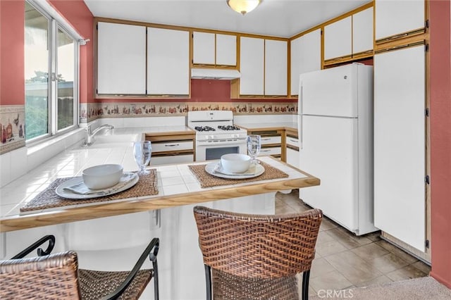 kitchen featuring sink, white appliances, white cabinets, and light tile patterned flooring