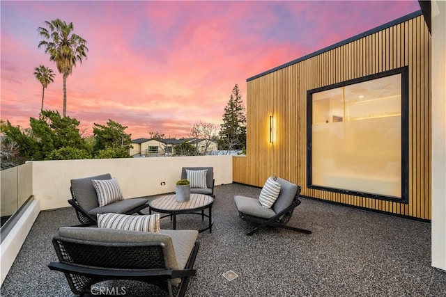 patio terrace at dusk featuring a balcony