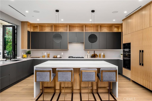 kitchen with sink, a center island, a breakfast bar area, and hanging light fixtures