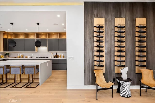 kitchen with gas stovetop, pendant lighting, light hardwood / wood-style flooring, and a breakfast bar area