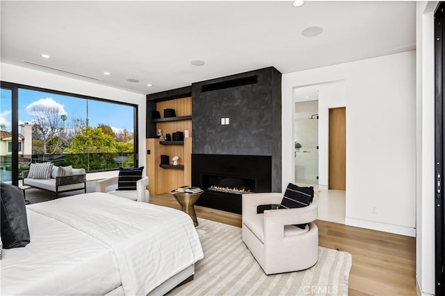 bedroom featuring a large fireplace and light hardwood / wood-style flooring