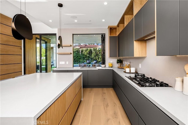 kitchen featuring black gas stovetop, decorative light fixtures, light hardwood / wood-style floors, sink, and gray cabinets