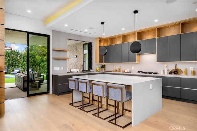 kitchen with a kitchen island, light hardwood / wood-style flooring, gray cabinets, and decorative light fixtures