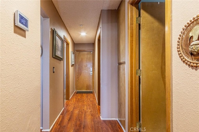 hallway featuring dark wood-type flooring and a textured ceiling