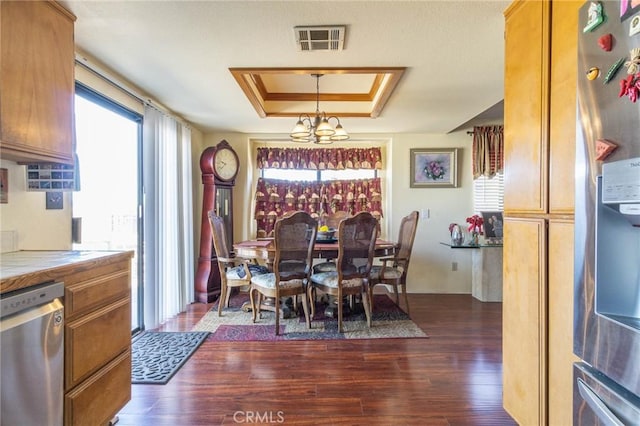 dining room with an inviting chandelier, a tray ceiling, and dark hardwood / wood-style flooring