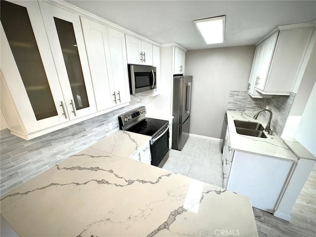 kitchen featuring white cabinetry, stainless steel appliances, tasteful backsplash, sink, and light stone counters