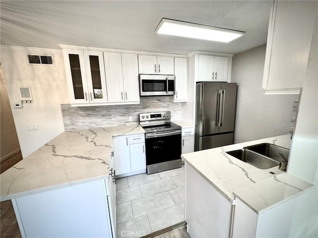 kitchen with white cabinets, sink, kitchen peninsula, stainless steel appliances, and light stone counters