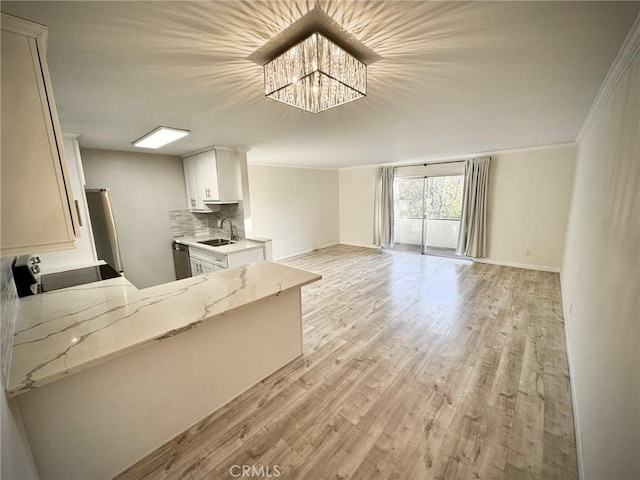 kitchen featuring light stone countertops, white cabinetry, tasteful backsplash, sink, and stainless steel dishwasher