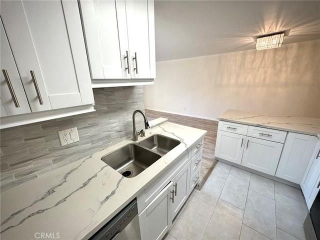 kitchen with sink, white cabinetry, light tile patterned floors, and light stone countertops