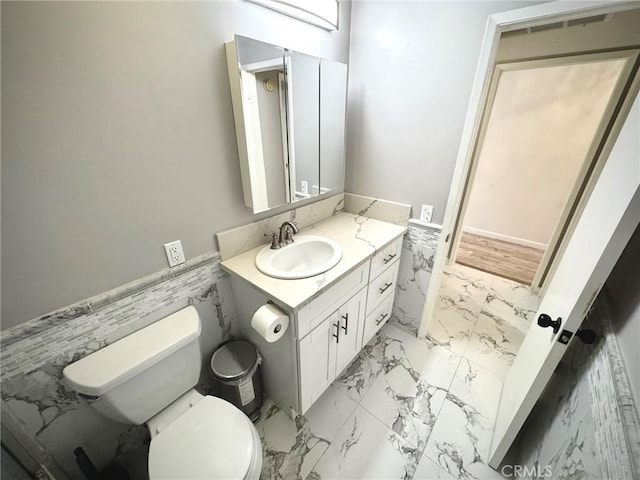 bathroom featuring toilet, vanity, and tile walls