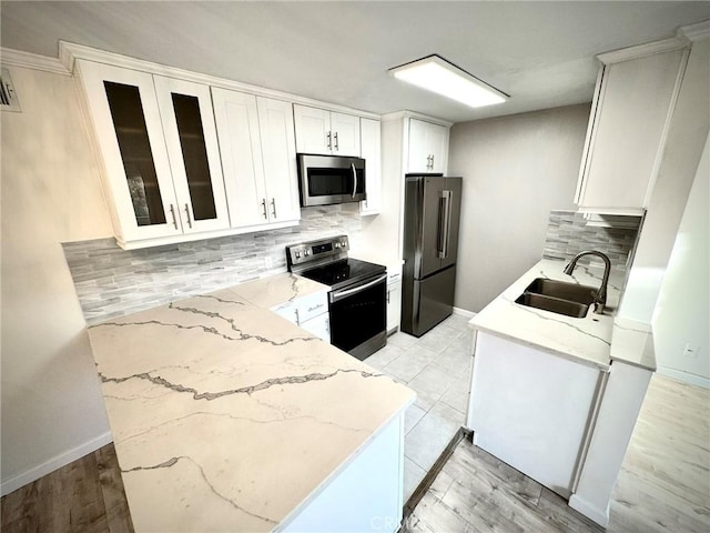 kitchen featuring white cabinets, stainless steel appliances, tasteful backsplash, sink, and light stone counters