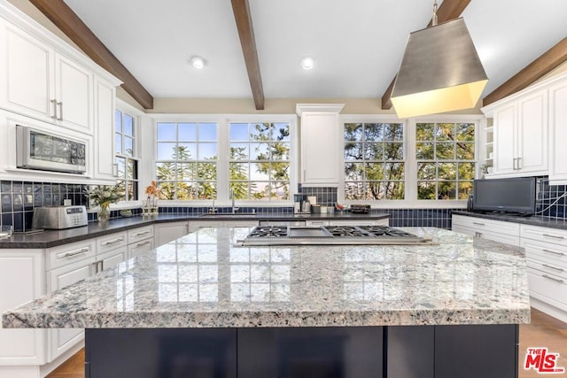 kitchen featuring a kitchen island, white cabinets, dark stone counters, and stainless steel appliances