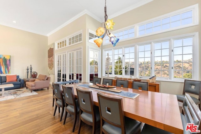 dining space with light hardwood / wood-style flooring, a notable chandelier, and ornamental molding