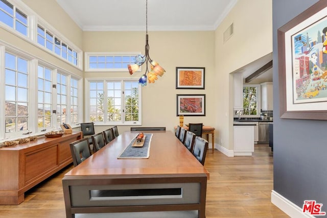 dining area featuring light hardwood / wood-style floors, ornamental molding, and an inviting chandelier