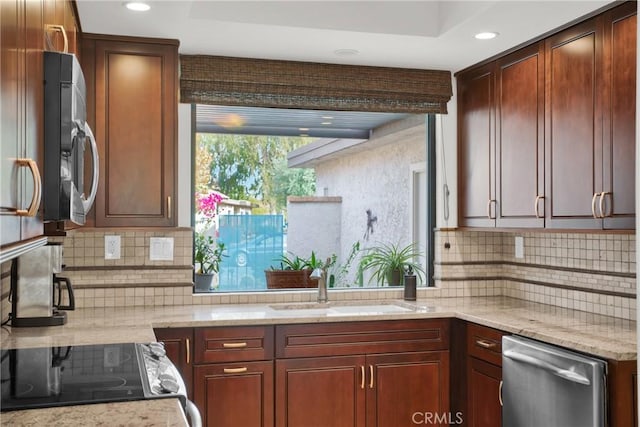 kitchen with light stone counters, sink, decorative backsplash, and stainless steel appliances