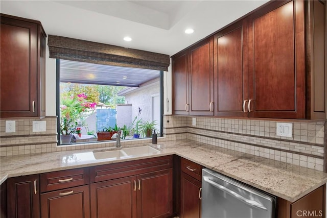 kitchen with light stone counters, stainless steel dishwasher, sink, and backsplash