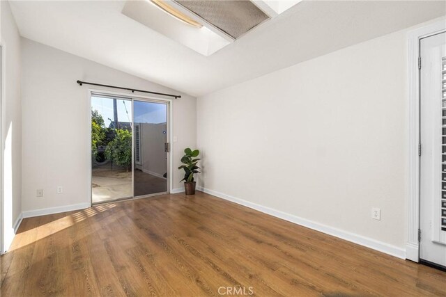 spare room with hardwood / wood-style flooring and lofted ceiling with skylight