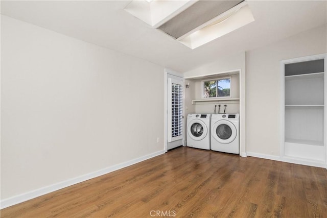 laundry area with hardwood / wood-style floors, a skylight, and independent washer and dryer