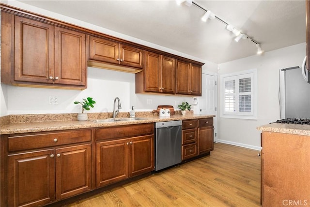 kitchen featuring sink, light wood-type flooring, light stone countertops, and appliances with stainless steel finishes