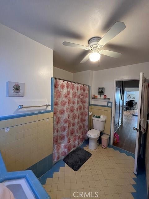 bathroom with ceiling fan, toilet, and tile walls