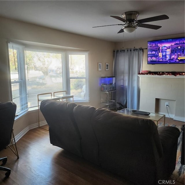 living room with hardwood / wood-style flooring, ceiling fan, and a tile fireplace