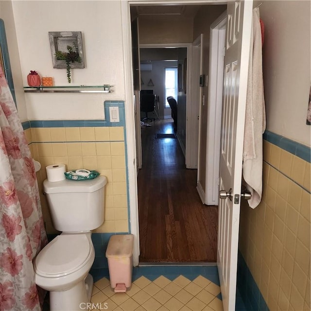 bathroom with tile walls, tile patterned floors, and toilet