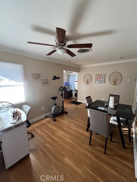 office space with dark wood-type flooring, ceiling fan, and crown molding