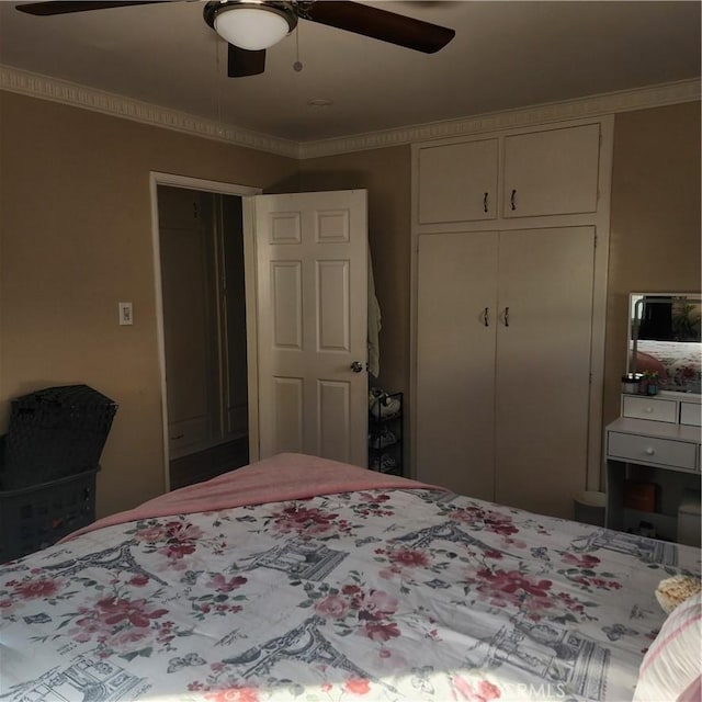 bedroom with ceiling fan, ornamental molding, and a closet