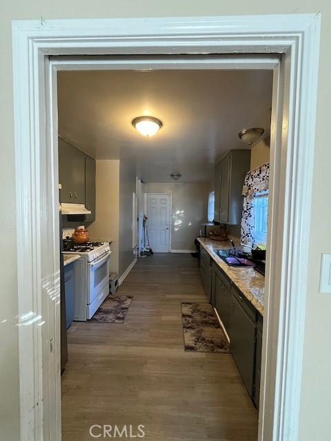 kitchen with sink, light hardwood / wood-style flooring, gray cabinetry, and white gas range oven