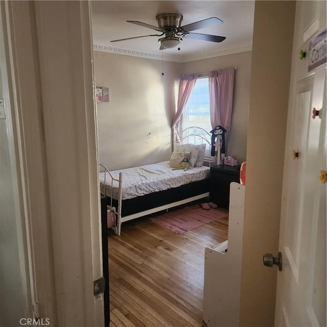 bedroom with crown molding, light wood-type flooring, and ceiling fan