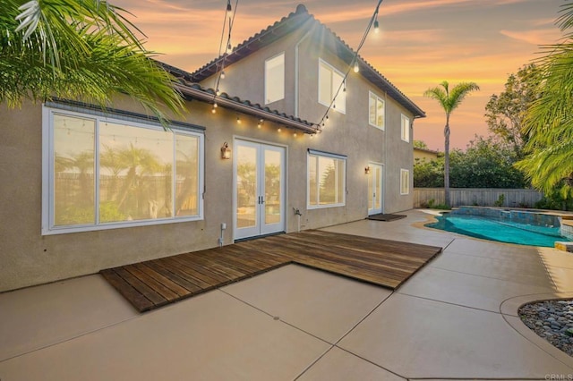 back house at dusk featuring a patio, a swimming pool side deck, and french doors