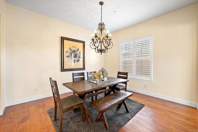 dining area featuring wood-type flooring and a notable chandelier