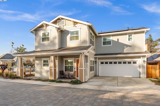 view of front of home featuring a garage, solar panels, and covered porch