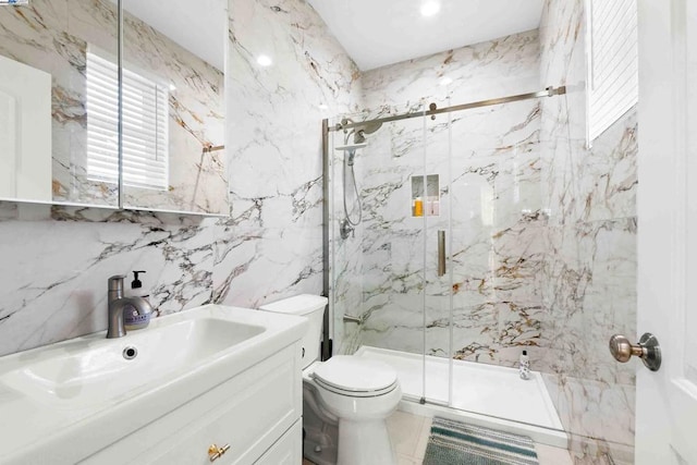 bathroom with a shower with door, vanity, tile walls, and toilet