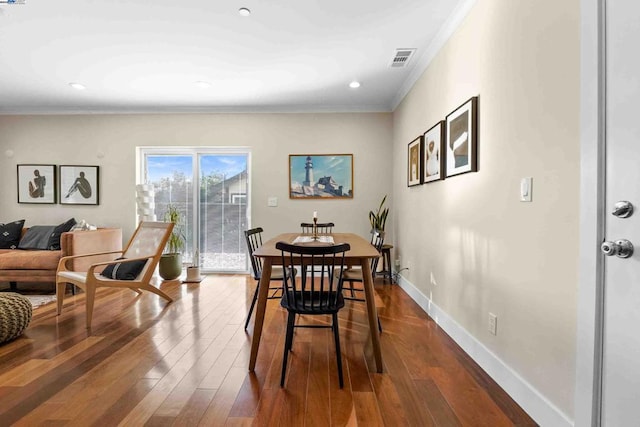 dining area featuring ornamental molding and dark hardwood / wood-style flooring